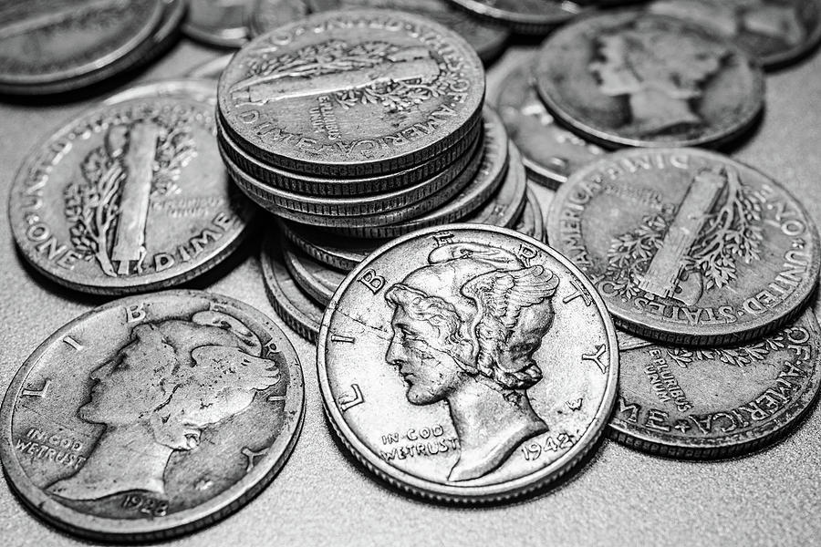 pile of silver mercury dimes showing various wear from circulation